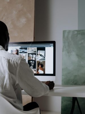 Back view of a man sitting at a computer, browsing images in a modern workspace.