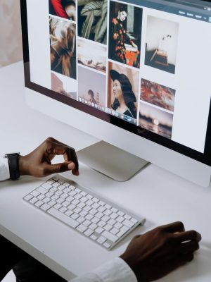 Man working on computer in modern office, viewing photography website. Clean and tech-focused environment.